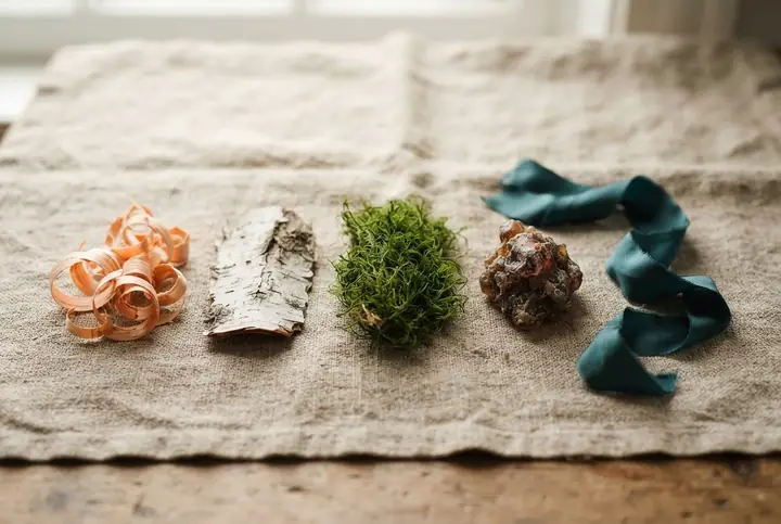 Cedar shavings, a curl of birch bark, a piece of oakmoss and a dark amber resin arranged on raw linen