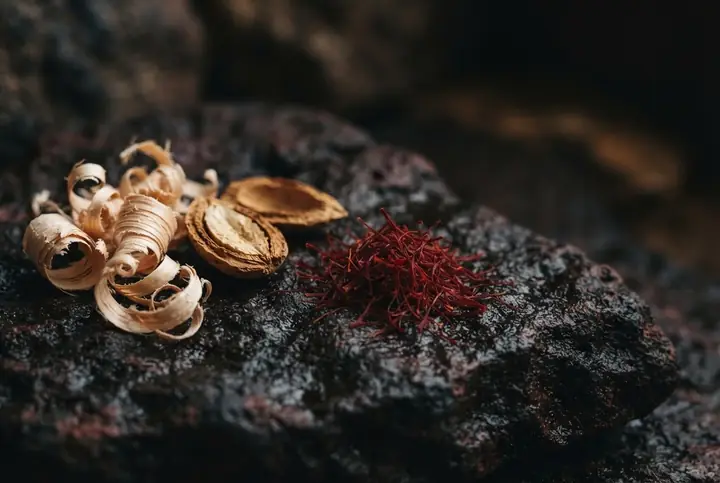 Saffron threads, split bitter almonds and pale cedar shavings arranged on dark red stone
